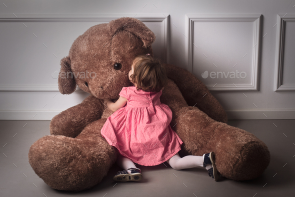 Little girl hugging a big teddy bear Stock Photo by macondoso PhotoDune